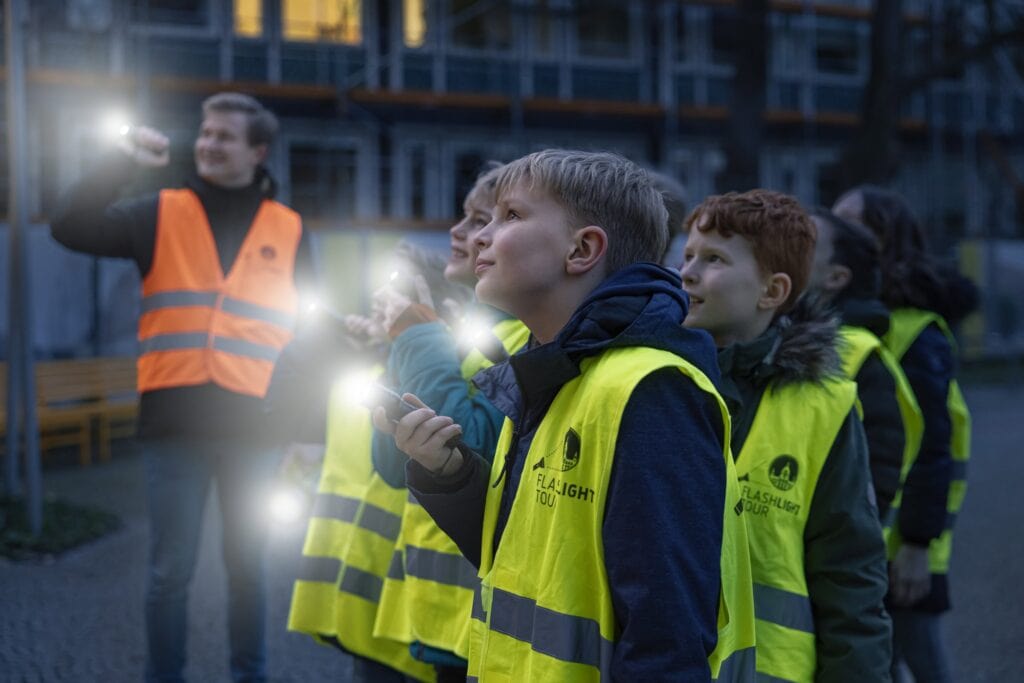 Kinder bei Baustellenbesichtigung mit Warnwesten und Taschenlampen.