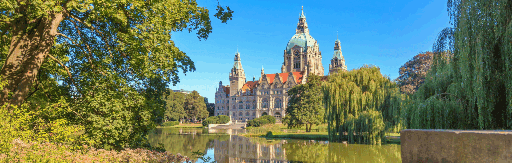 Blick auf das historische Rathaus im Stadtzentrum von Hannover, umgeben von Natur.