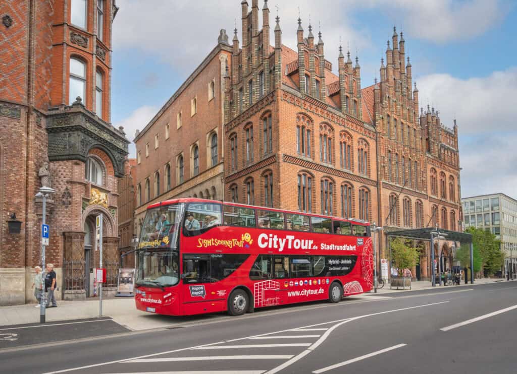 Historisches Rathaus Hannover mit rotem Doppeldeckerbus davor.