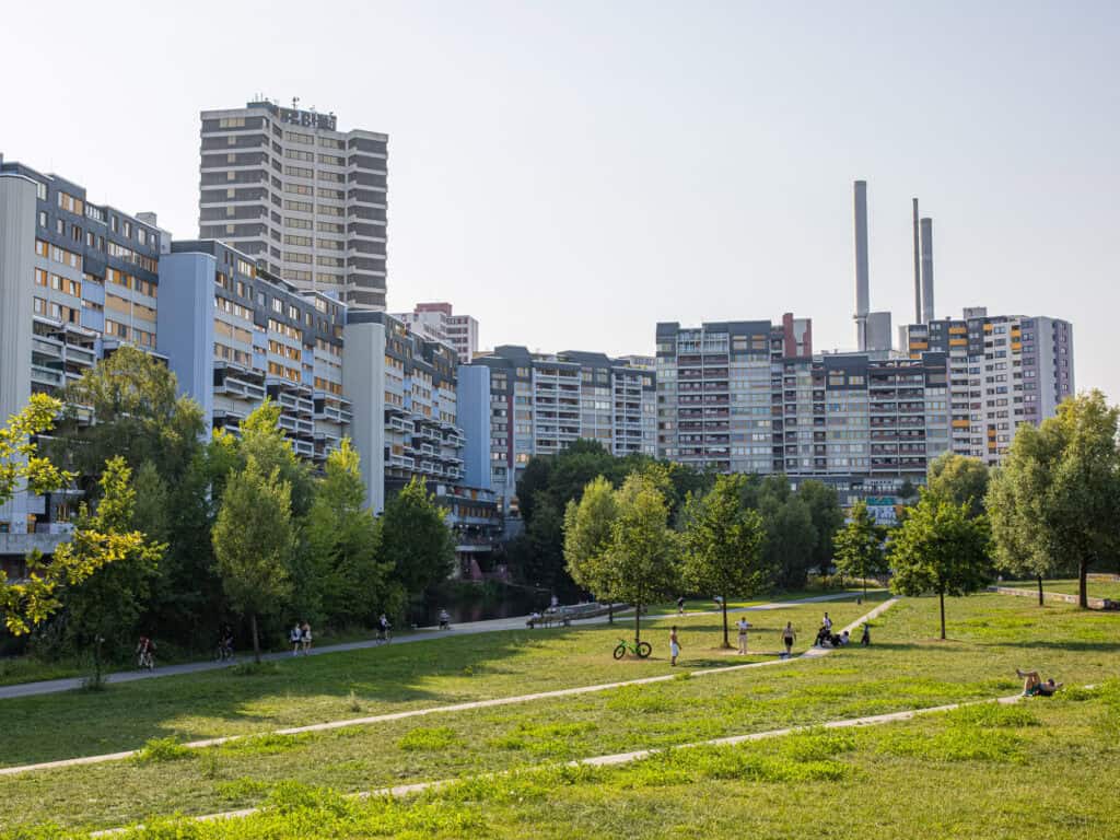 Grüner Stadtpark in Hannover mit modernen Hochhäusern im Hintergrund, ideal für Erholung und Spazier.