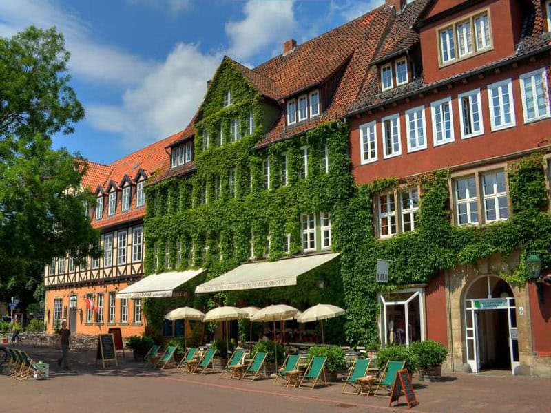 Historische Gebäude in Hannover mit grünen Fassaden und Straßencafés.