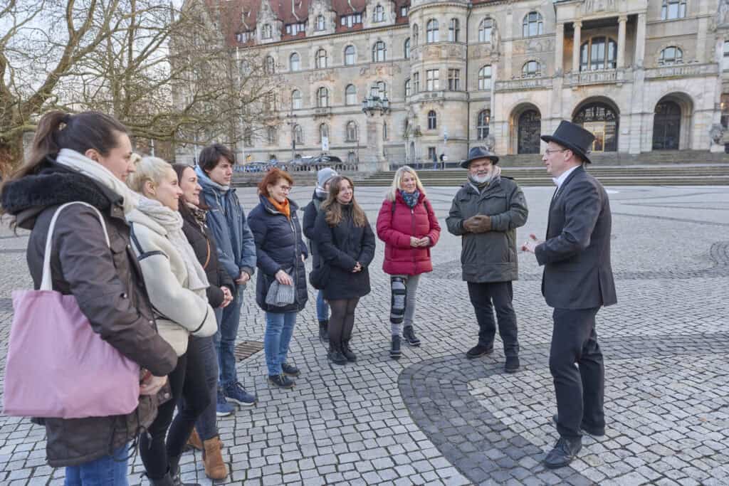 Gruppe von Touristen bei einer Stadtführung in Hannover, mit Guide vor historischen Gebäuden.
