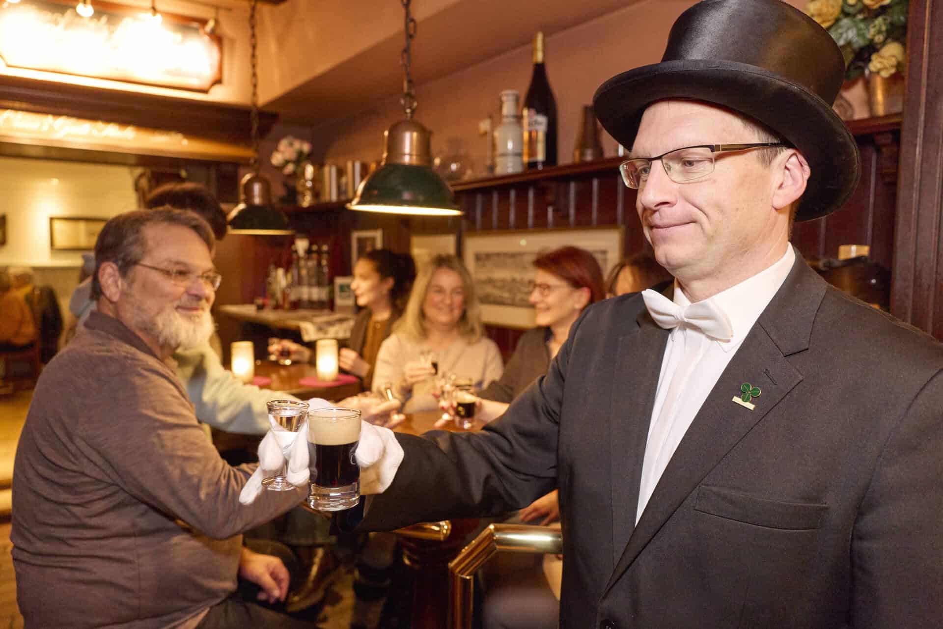 Mann in Zylinder serviert Bier in gemütlicher Bar während der Bruchmeister Tour.