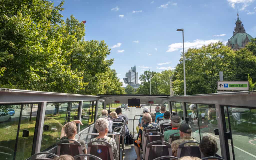 Doppeldecker-Bus in Hannover bei Stadtrundfahrt, Touristen genießen die Stadtansicht.