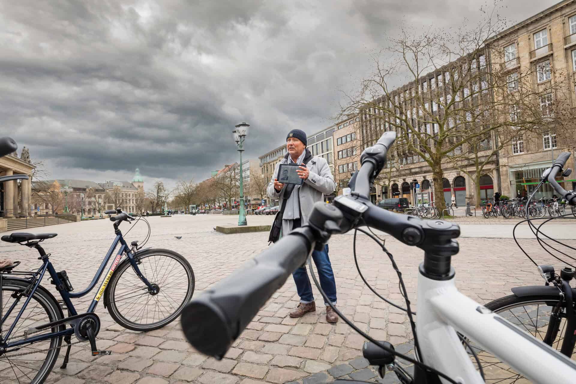 Frau mit Tablet vor Fahrrädern bei der Krimitour in Hannover.