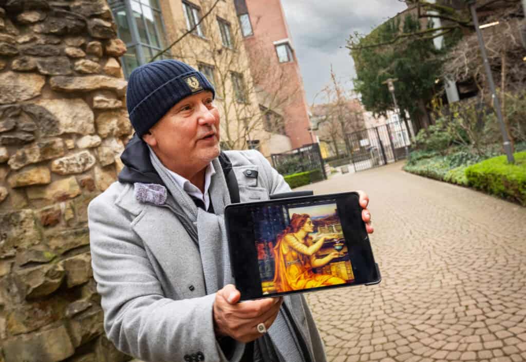 Mann zeigt auf Smartphone mit Krimi-Szene, unterwegs in Hannover.