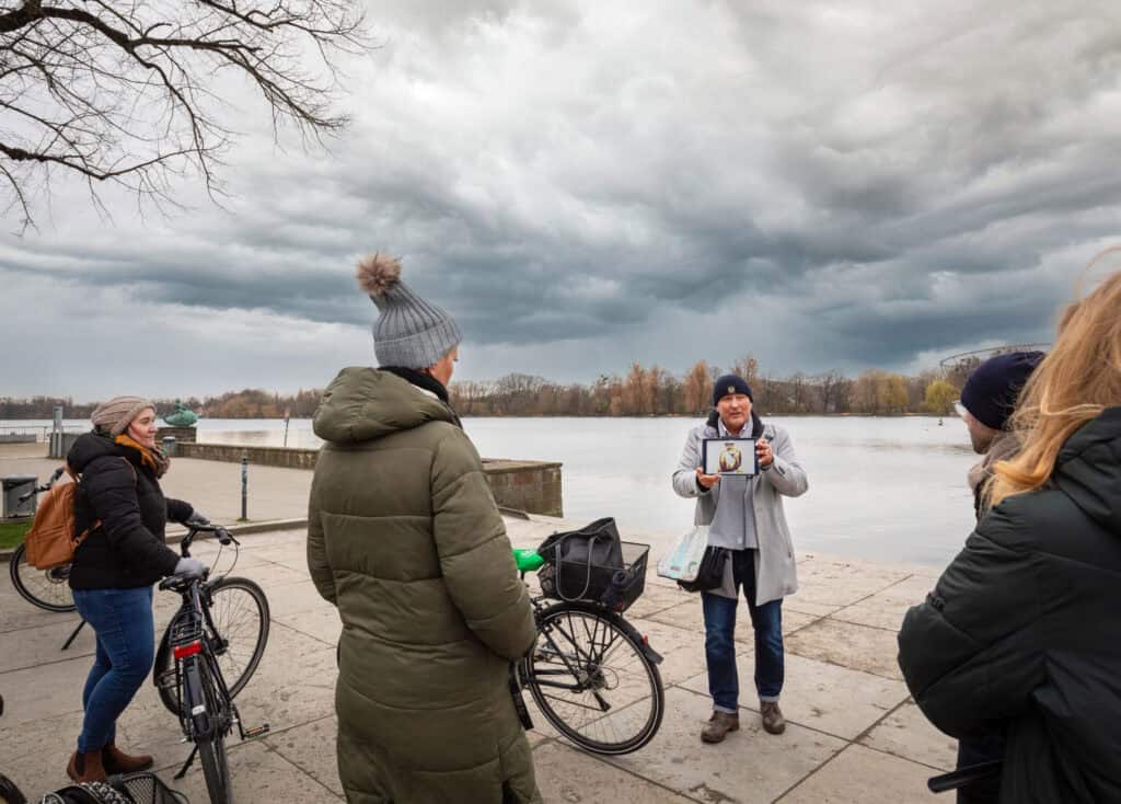 Gruppe von Menschen bei einer Krimitour auf Fahrrädern am Fluss in Hannover.