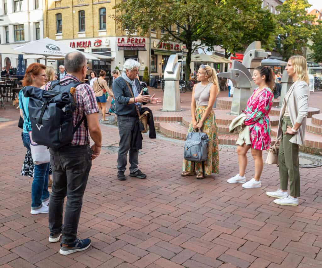 Touristen in Hannover Oststadt hören einem Stadtführer zu, um die Sehenswürdigkeiten der Oststadt zu.