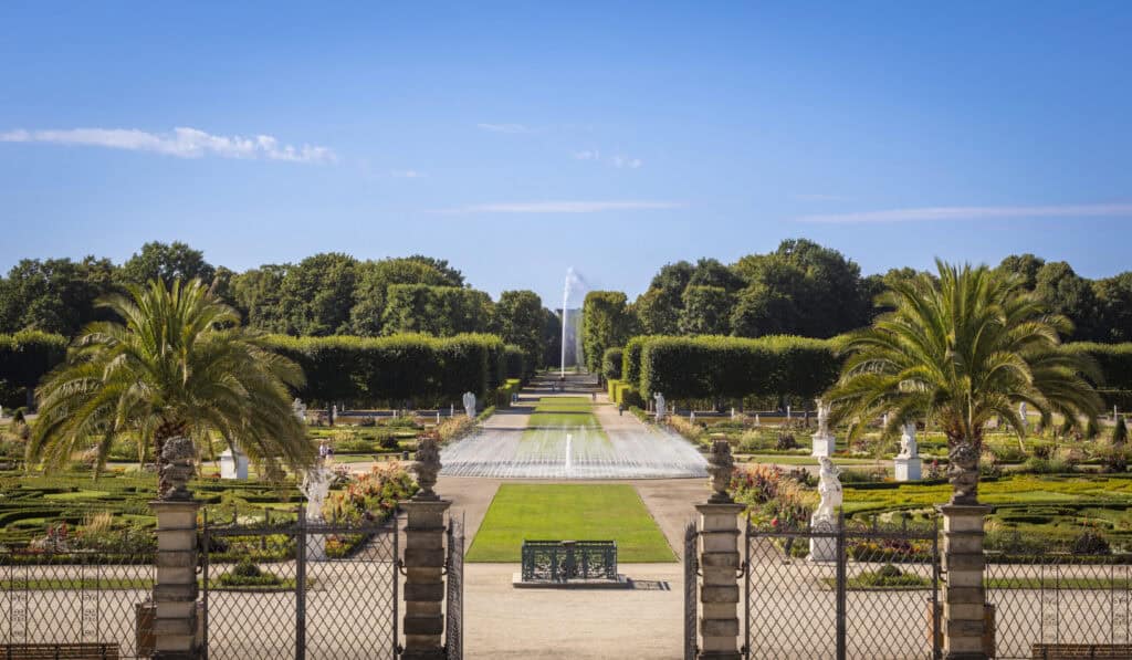 Blick auf die Herrenhäuser Gärten mit Palmen und gepflegten Beeten in Hannover.