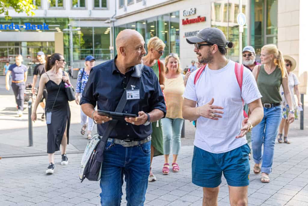 Zwei Männer im Gespräch auf der Straße während einer Stadtführung in Hannover.