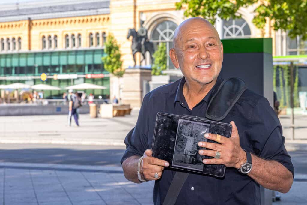 Mann mit Tablet in Hannover, historische Gebäude im Hintergrund.