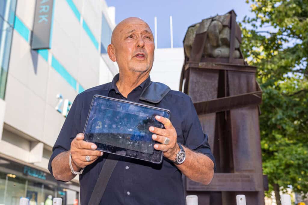 Mann mit Tablet vor Skulptur bei einer Kriminalitätsführung in Hannover.
