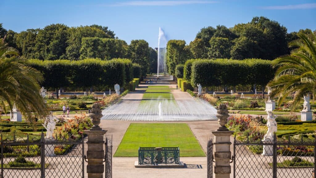 Blick auf den königlichen Garten in Herrenhausen mit Springbrunnen und gepflegten Blumen.