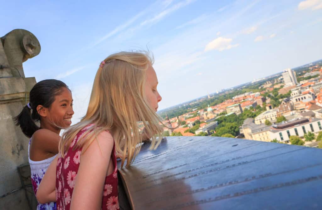 Zwei Kinder bei einer Stadtführung in Hannover, Blick auf die Stadt vom Wahrzeichen aus.