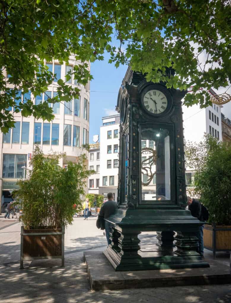 Historischer Uhrturm in Hannover mit moderner Stadt im Hintergrund.