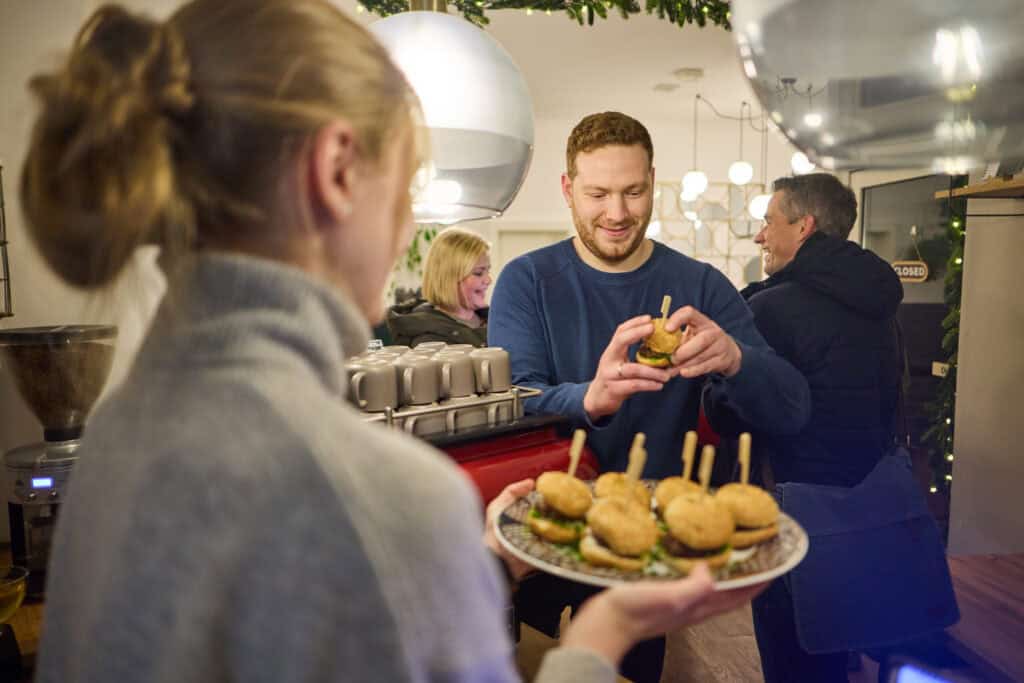 Freundlicher Kellner serviert kleine Burger in der Südstadt von Hannover.