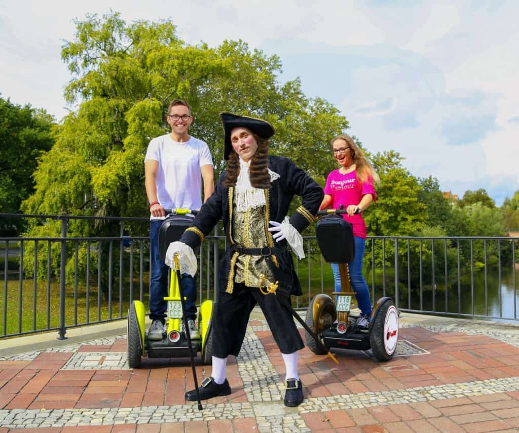 Zwei Personen auf Segways und eine Person im historischen Kostüm in Hannover.