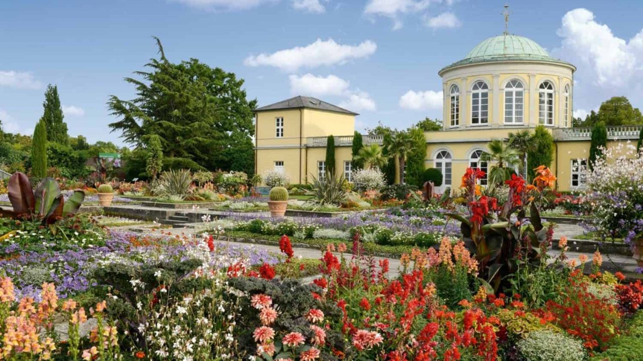 Upea näkymä Suurelle puutarhalle, jossa on värikkäitä kukkia ja historiallisia rakennuksia Hannoverissa.