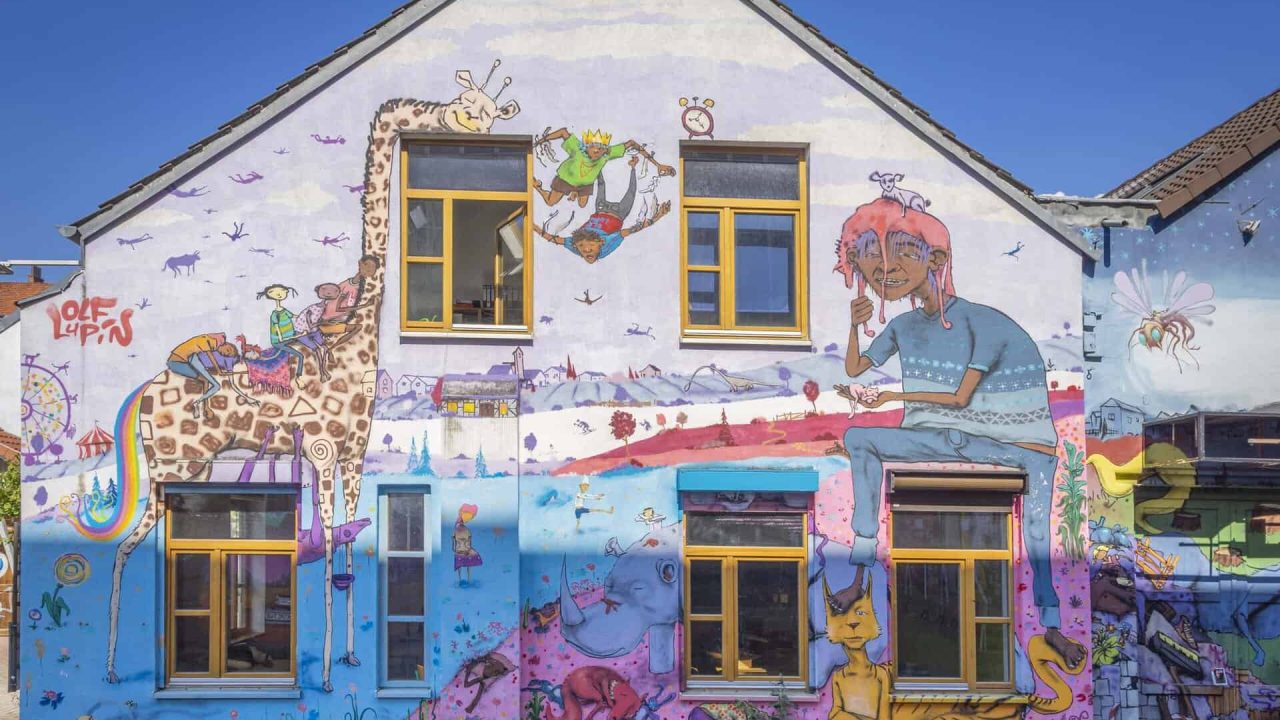 Hannover'de bir evin cephesinde renkli sokak sanatı, hayvanlar ve fantezi ile canlı grafiti sanatı.