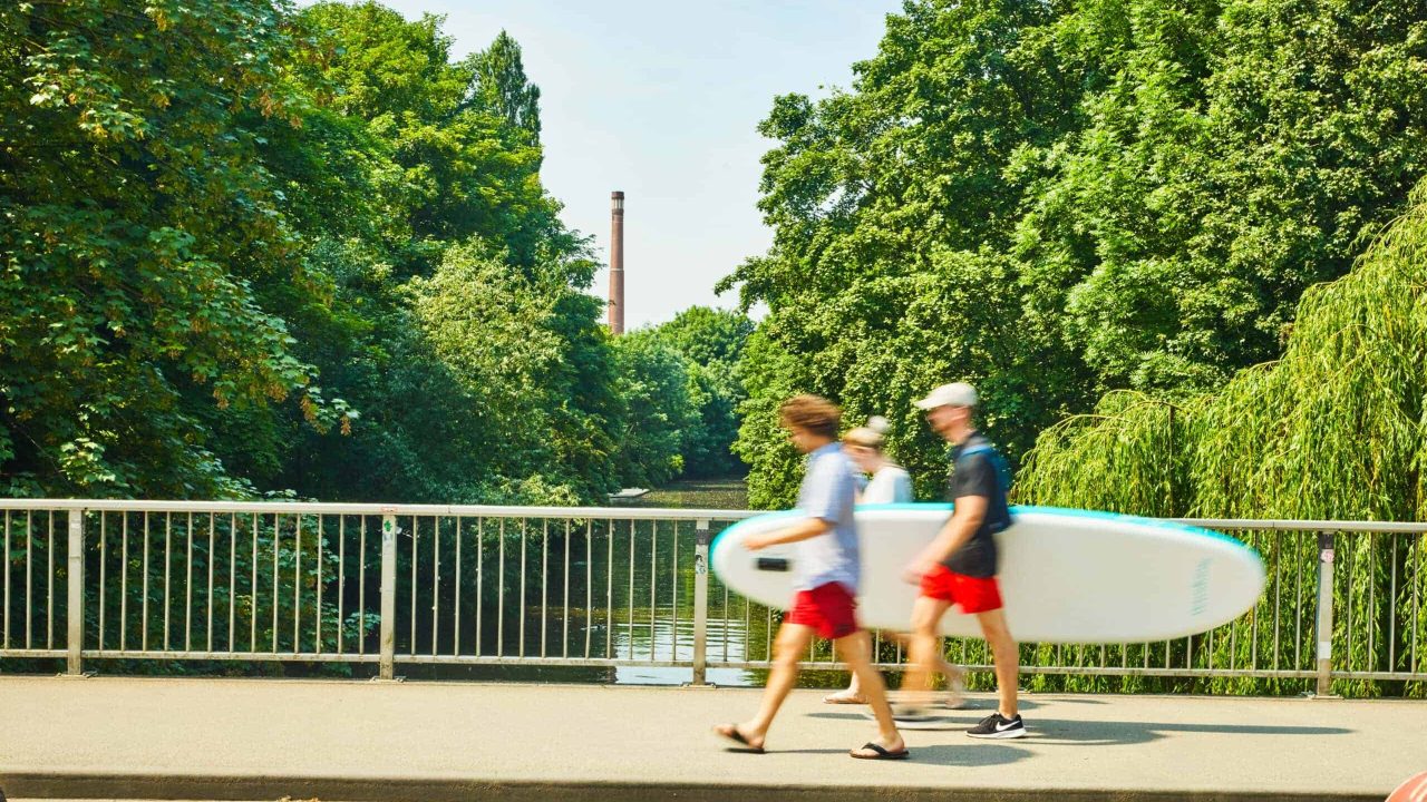 Bambini con tavola da surf sulla riva del fiume ad Hannover, natura e tempo libero.