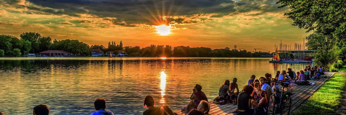 汉诺威 Maschsee 的日落，人们坐在水边欣赏美景。.