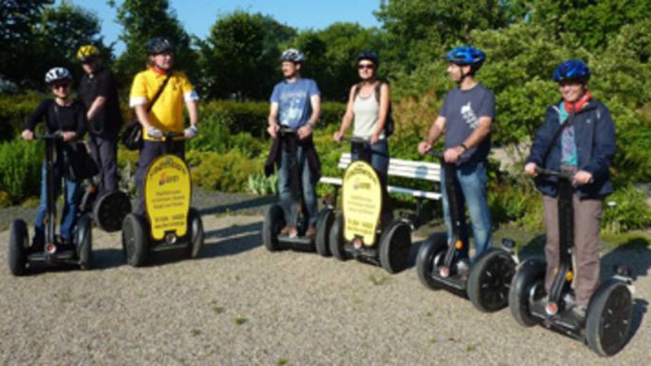 Gruppe von Menschen auf Segways bei Stadtführung im Deister, Naturkulisse im Hintergrund.